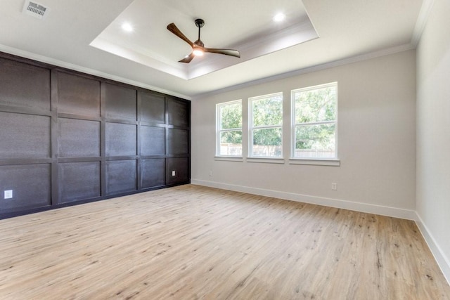 spare room with ceiling fan, ornamental molding, a raised ceiling, and light wood-type flooring