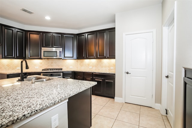 kitchen featuring light stone counters, sink, decorative backsplash, appliances with stainless steel finishes, and light tile patterned floors