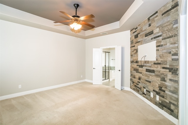 unfurnished room with ceiling fan, light colored carpet, and a raised ceiling