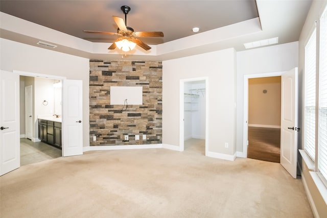 unfurnished bedroom with a tray ceiling, multiple windows, and a spacious closet