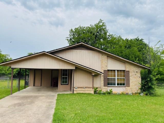 view of front facade with concrete driveway, a carport, fence, and a front yard