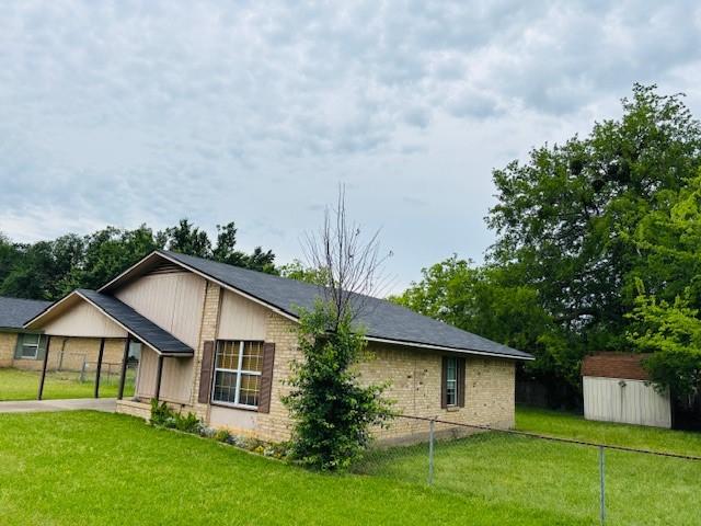 view of property exterior featuring fence, an outdoor structure, a yard, concrete driveway, and a shed