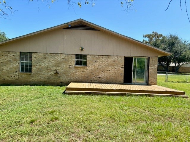 back of property featuring a wooden deck and a yard