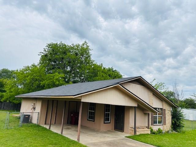 rear view of house featuring concrete driveway, fence, a lawn, and a carport