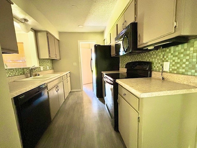 kitchen with light hardwood / wood-style flooring, black appliances, tasteful backsplash, and sink