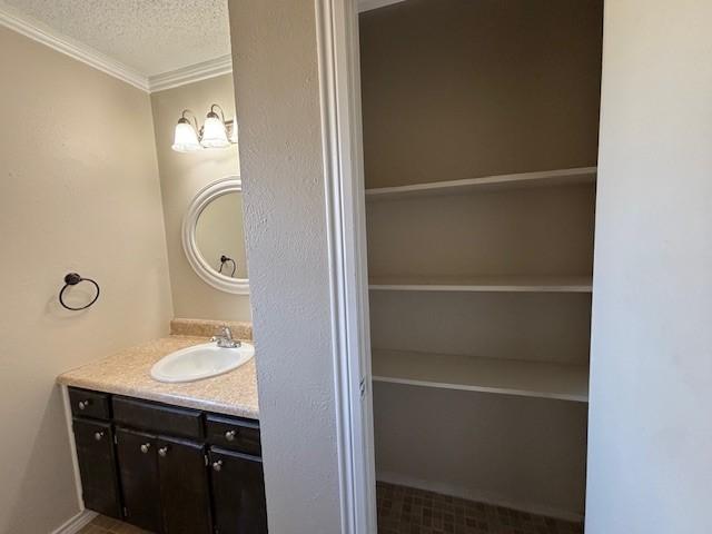 bathroom featuring ornamental molding, a textured ceiling, and vanity