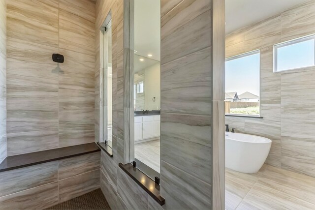 bathroom with plus walk in shower, vanity, tile walls, and tile patterned flooring