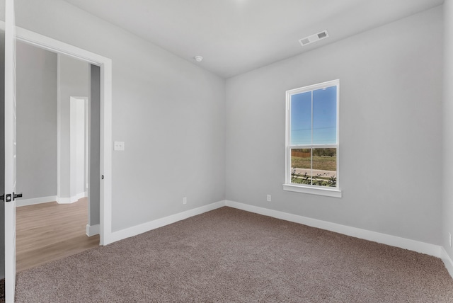 carpeted empty room featuring visible vents and baseboards