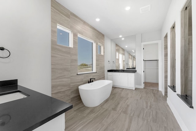 bathroom with vanity, tile walls, and a tub