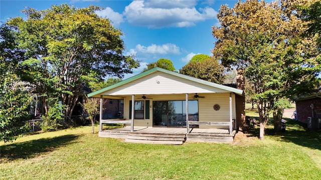 back of property with a yard, a deck, and ceiling fan