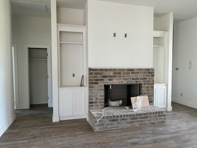 unfurnished living room featuring a brick fireplace and dark hardwood / wood-style flooring