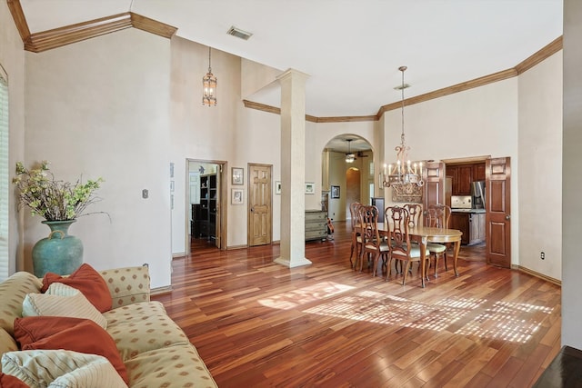 living room with ornamental molding, a towering ceiling, hardwood / wood-style flooring, and ornate columns