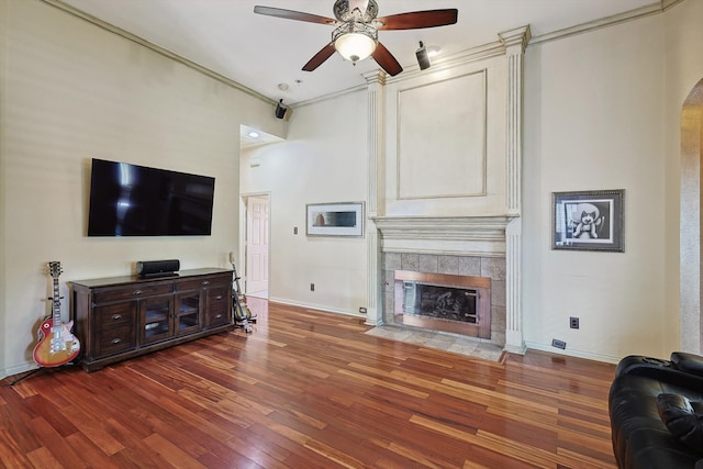 living room with ceiling fan, crown molding, dark hardwood / wood-style flooring, and a tile fireplace