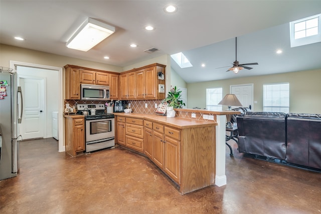 kitchen featuring kitchen peninsula, concrete flooring, ceiling fan, and appliances with stainless steel finishes