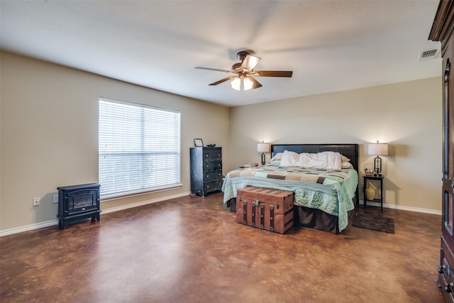 bedroom with a wood stove and ceiling fan