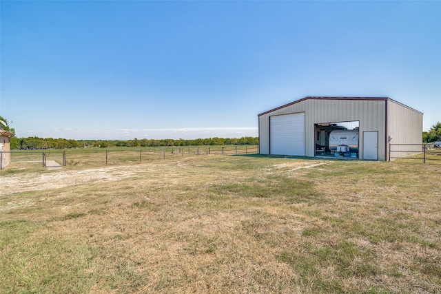 view of yard featuring a garage, a rural view, and an outbuilding