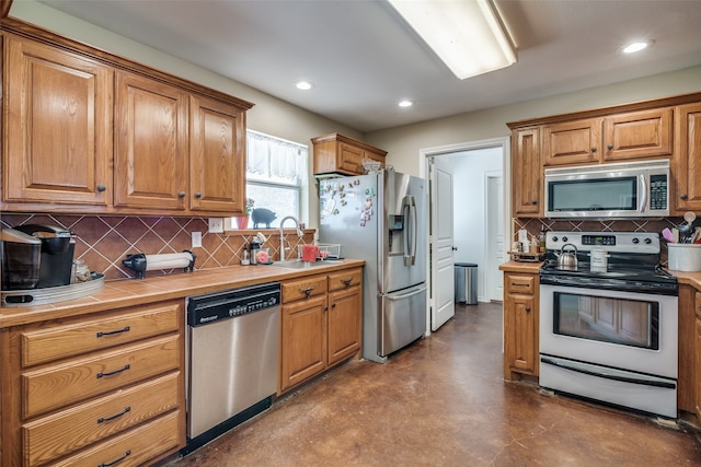 kitchen featuring sink, backsplash, concrete flooring, stainless steel appliances, and tile counters