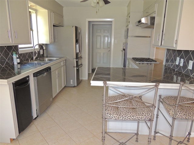 kitchen featuring decorative backsplash, kitchen peninsula, stainless steel appliances, range hood, and ceiling fan