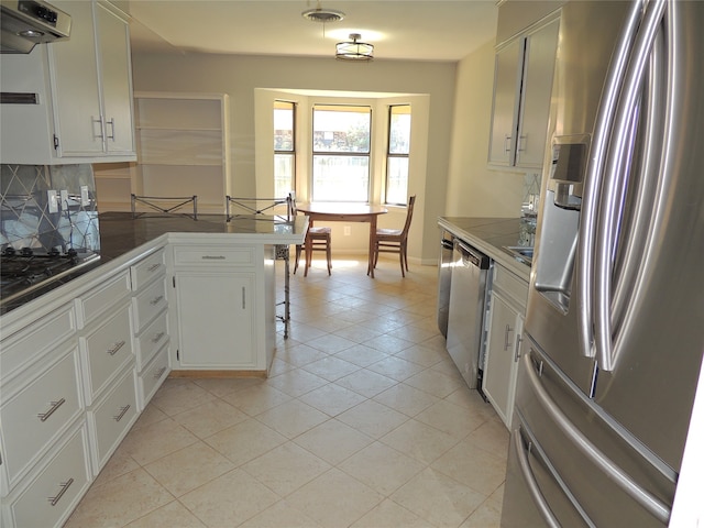 kitchen featuring white cabinetry, range hood, and stainless steel appliances