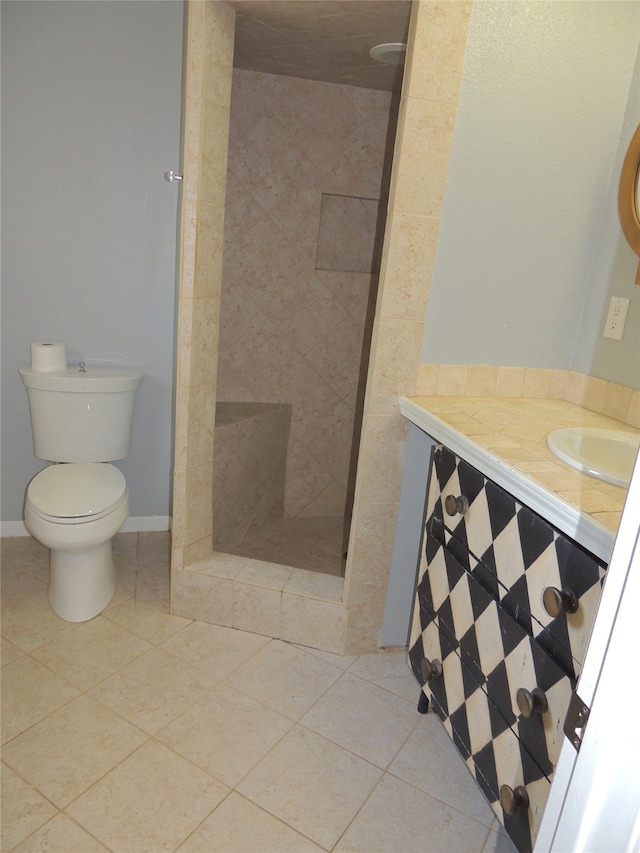 bathroom featuring vanity, tile patterned floors, toilet, and tiled shower