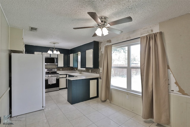 kitchen featuring a textured ceiling, sink, ceiling fan with notable chandelier, hanging light fixtures, and stainless steel appliances