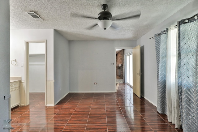 empty room featuring ceiling fan, a textured ceiling, and dark tile patterned flooring