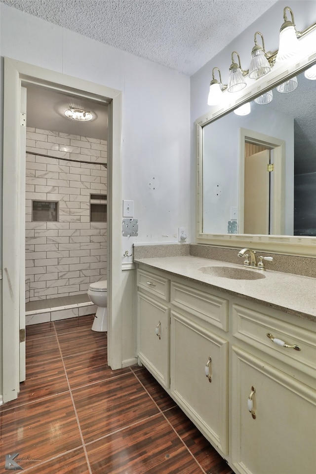 bathroom featuring a textured ceiling, vanity, and toilet