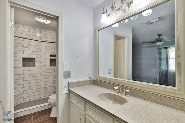 bathroom with vanity, a textured ceiling, a tile shower, toilet, and hardwood / wood-style floors