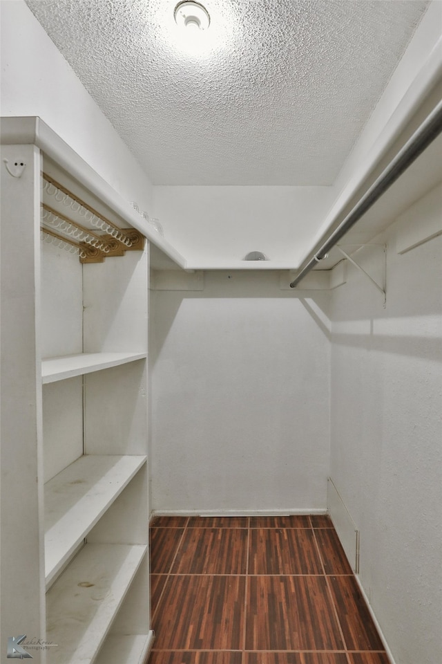 walk in closet with dark hardwood / wood-style floors