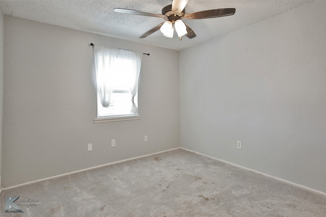 spare room featuring ceiling fan, light colored carpet, and a textured ceiling