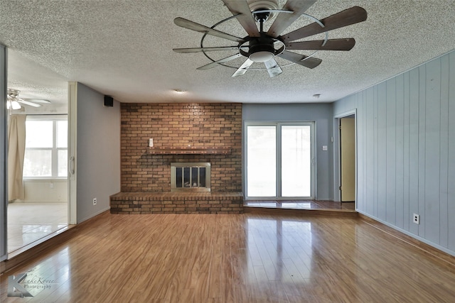 unfurnished living room featuring wood-type flooring, ceiling fan, and a textured ceiling