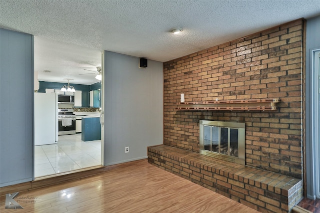 unfurnished living room with ceiling fan, light hardwood / wood-style floors, a fireplace, and a textured ceiling