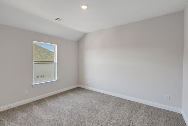 carpeted spare room featuring vaulted ceiling