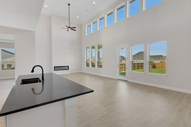 unfurnished living room featuring a towering ceiling, light hardwood / wood-style flooring, and ceiling fan