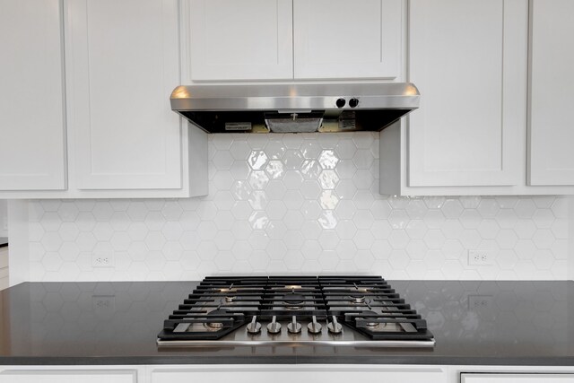 kitchen with white cabinets, built in microwave, an island with sink, and extractor fan