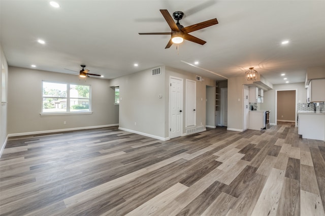 unfurnished living room featuring ceiling fan, sink, and hardwood / wood-style floors