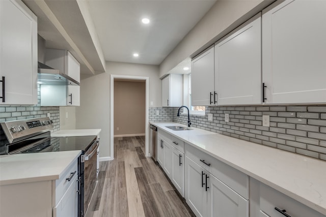 kitchen with stainless steel appliances, white cabinetry, light hardwood / wood-style floors, and sink