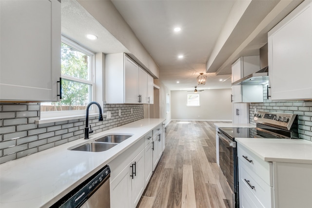 kitchen featuring white cabinets, sink, appliances with stainless steel finishes, light wood-type flooring, and decorative backsplash