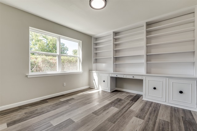 unfurnished office with wood-type flooring and built in desk