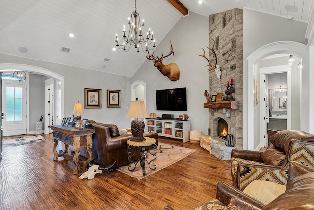 living room featuring beamed ceiling, hardwood / wood-style floors, a stone fireplace, and high vaulted ceiling