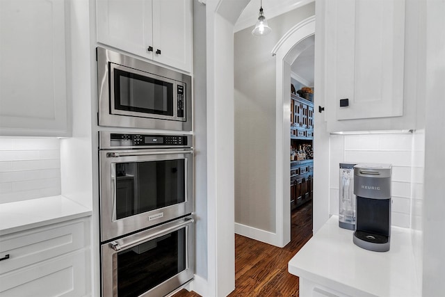 kitchen with tasteful backsplash, white cabinetry, pendant lighting, stainless steel appliances, and dark hardwood / wood-style floors