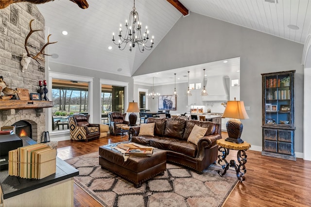 living room featuring a fireplace, high vaulted ceiling, a chandelier, hardwood / wood-style flooring, and beam ceiling