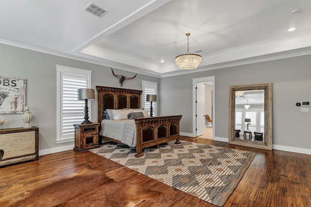 bedroom featuring hardwood / wood-style flooring, a raised ceiling, and ornamental molding