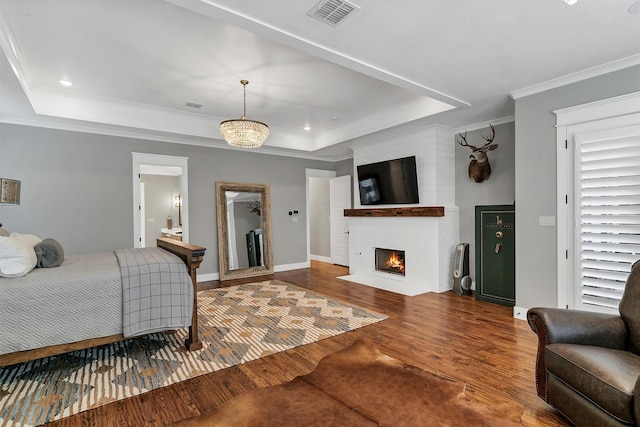 bedroom with multiple windows, wood-type flooring, ornamental molding, and a raised ceiling