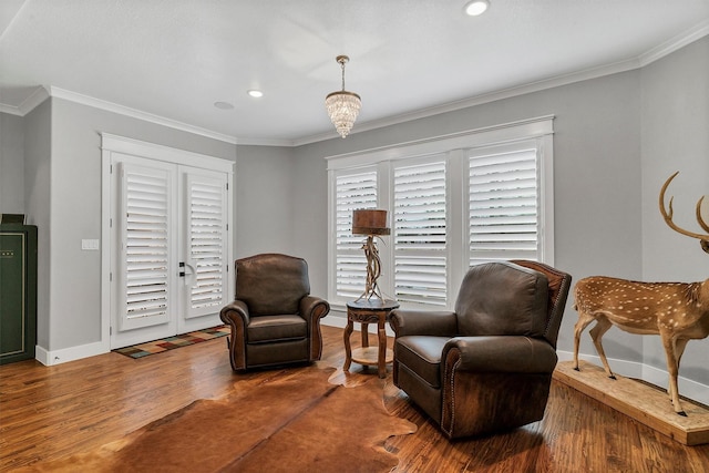 living area with hardwood / wood-style floors and ornamental molding