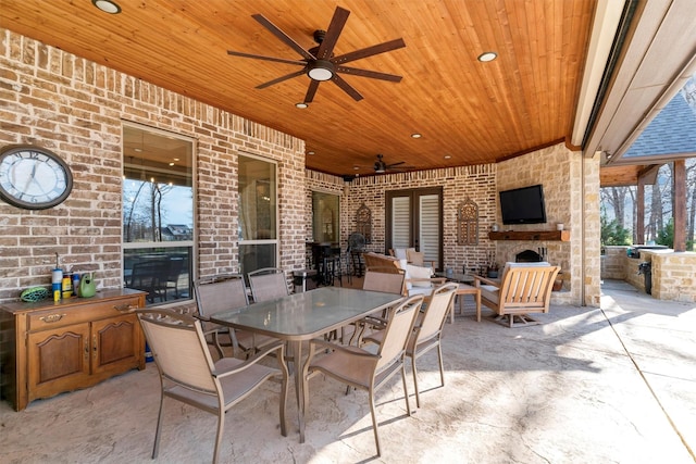 view of patio featuring exterior kitchen, an outdoor stone fireplace, and ceiling fan