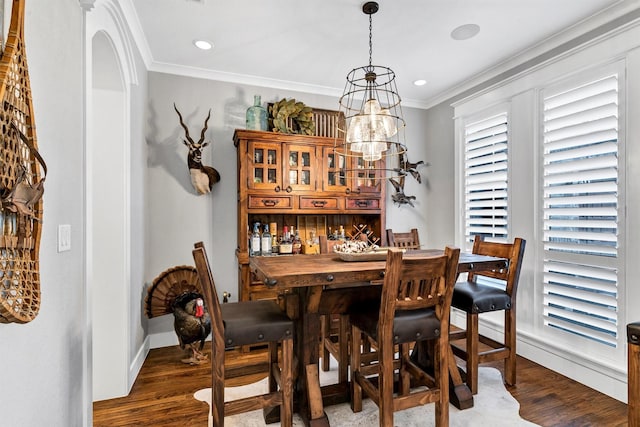 dining space with dark hardwood / wood-style flooring, ornamental molding, and a chandelier