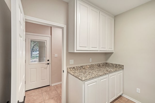 interior space with white cabinetry, light tile patterned floors, and light stone countertops