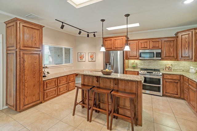 kitchen featuring a kitchen breakfast bar, hanging light fixtures, light stone countertops, appliances with stainless steel finishes, and a kitchen island