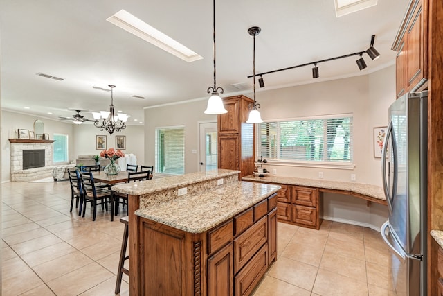 kitchen featuring stainless steel fridge, a center island, decorative light fixtures, and light tile patterned floors